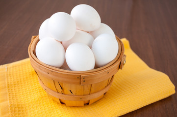A lot of white chicken eggs in a basket on the table