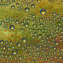 Spheres of different diameters orange, yellow and gold colors and their green reflections are...