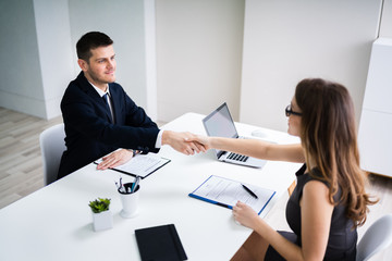 Businesswoman Shaking Hands With Partner In Office