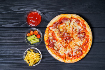 Italian pizza with cheese, cucumbers and French fries lies on a dark background. Food delivery