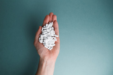 White tablets on a blue background are isolated. Hand with a tablet. A pile of pills in the open palm. Virus protection and 2019-ncov.