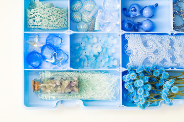 Container with shells, fish figures, crystals, stones, lace ribbons, artificial flowers and other collectibles