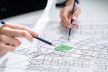 Human Hand Holding Pencil Over Cadastre Map