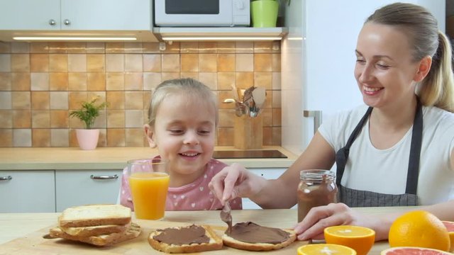 Mother preparing healthy breakfast her daughter - toast with peanut butter
