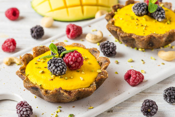 homemade raw mango cakes with frozen berries, pistachio and mint. healthy vegan gluten free food concept