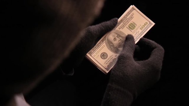 Thief taking the money from stolen wallet .