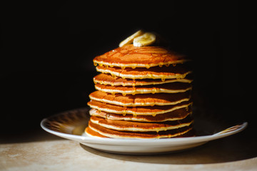 Close-up delicious pancakes, decorated with banana and honey. Bl
