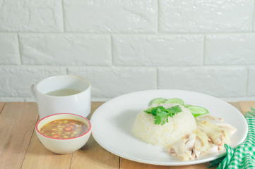 Chicken rice with dipping sauce and soup placed on a wooden table