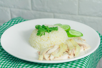 Chicken rice with dipping sauce and broth laid on a green tablecloth