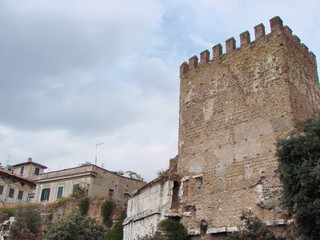 Bottom view of the mighty walls of ancient Rome against a cloudy sky.