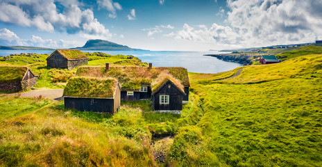 Sunny morning view of typical turf-top houses. Panoramic summer scene of outskirts of Torshavn city, capital of Faroe Islands, Kingdom of Denmark, Europe. Traveling concept background..