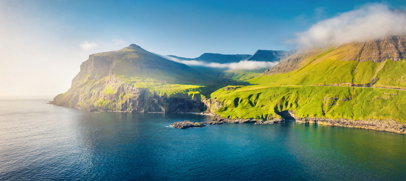 View from flying drone. Misty morning scene of Vagar island. Colorful summer scene of Faroe Islands, Kingdom of Denmark, Europe. Traveling concept background