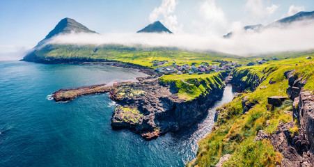 Incredible morning view of Gjogv village. Foggy summer scene of Eysturoy island. Bright panoramic...