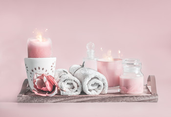 Pastel pink spa setting with candles,towels and cosmetic products. Beauty and skin care concept