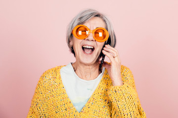 happy young style elderly grandma with orange sunglasses and modern looking laughing on the phone - obrazy, fototapety, plakaty
