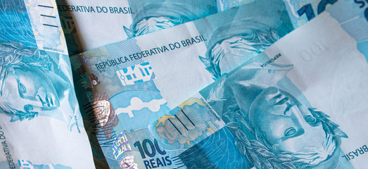 Textura e fundo azul com cédulas de cem reais do Brasil