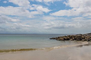 Fototapeta na wymiar White Sandy Beach Seascape with Clouds and Rocks