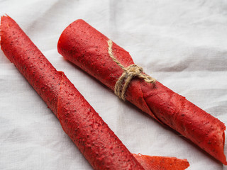 Red strawberry fruit leather rolls lie on the brown sacking