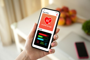 female hand holding phone with app heart and activity