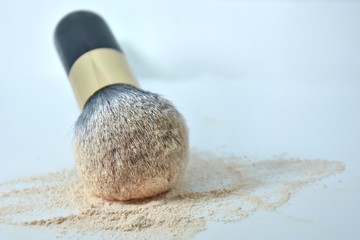 Makeup brush with loose powder on a white background