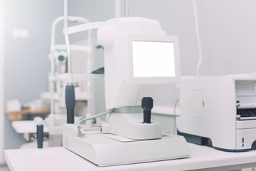 Auto Kerato Refractometer standing on a table in doctors office with empty screen mock up. It is designed to measure eye refraction, curvature and diameter of the patient’s cornea