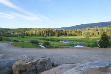 Golf course with blue sky and clouds, rocks in foreground, Clearwater Canada