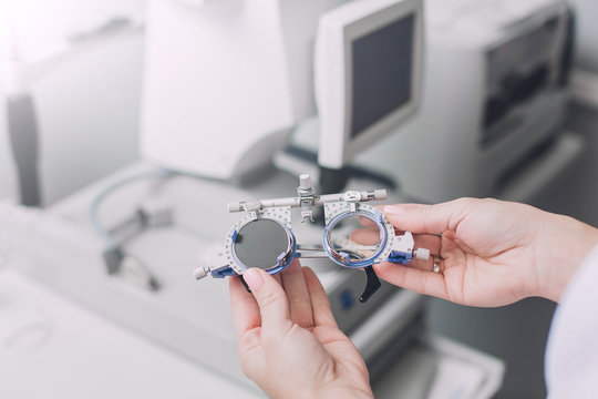 Ophthalmologist or optometrist in the clinic office holding in hands special glasses for  checking visual acuity on a background of the auto kerato refractometer
