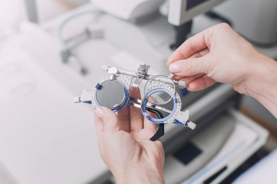 Ophthalmologist or optometrist in the clinic office holding in hands special glasses for  checking visual acuity on a background of the auto kerato refractometer