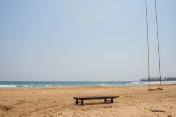 sunbed and swing under palm trees on the ocean
