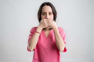 Young woman medical professional nurse or doctor dressed with pink hospital clothes in the speak no Evil