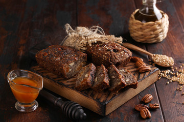 Healthy food. Sliced dark bread on a wooden board. Bread made from green buckwheat, nuts, honey, dried fruits and poppy seeds. Rustic. Background image, copy space