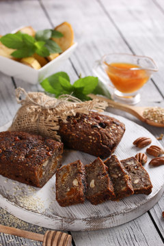 Healthy food. Sliced dark bread on a light wooden board. Bread made from green buckwheat, nuts, honey, dried fruits. Banana with mint on a white plate. Rustic. Background image, copy space
