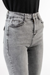 girl in jeans shows jeans on a white background close-up, gray jeans