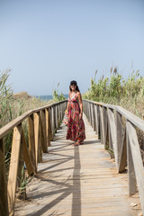 Mujer joven vestida de verano disfrutando de la playa del Mediterráneo en cadiz