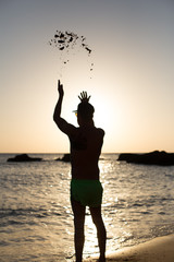 Hombre joven en la playa con gafas de sol y gorra disfrutando de la costa mediterránea de Cadiz,...