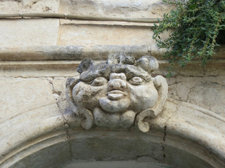 kissing head above a door in the streets of Ostuni