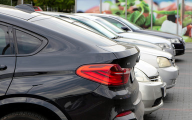 Cars stand in a row at a city parking lot. Detail. Close-up.