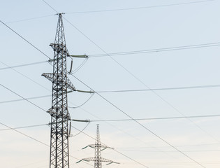 Supports high-voltage power lines against the blue sky.