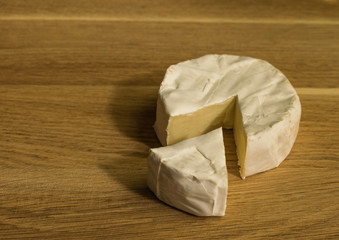 Fresh brie cheese with white mold on a white background on table