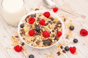 Breakfast Served in the morning with corn flakes Whole grains and raisins with milk in cups and Strawberry, Blueberry, Raspberry, Kiwi on the wood table,Diet food or healthy food in the morning.