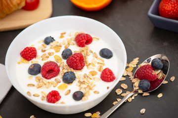 Breakfast Served in the morning with Coffee, Butter croissant and corn flakes Whole grains and raisins with milk in cups and Strawberry, Raspberry, Kiwi, Fresh Orange Juice on the breakfast table.