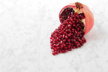  beautifully chopped pomegranate and its seeds, aesthetically laid out on a marble table.