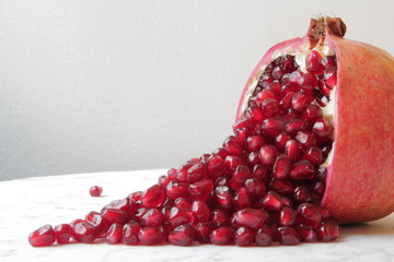  beautifully chopped pomegranate and its seeds, aesthetically laid out on a marble table.