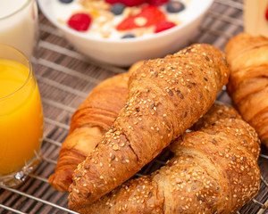 Breakfast Served in the morning with Fruit Yogurt, Butter croissant and corn flakes Whole grains and raisins with milk in cups and Strawberry, Raspberry, Kiwi, Fresh Orange Juice on breakfast table