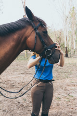 Obraz premium Young woman hugging her horse in stables before a ride