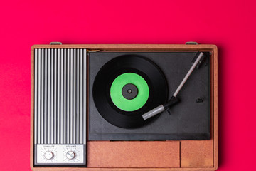 Retro vinyl player and turnable on a red background. Entertainment 70s. Listen to music. Top view.