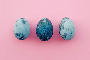 Natural dyed blue colored eggs on pastel pink background.