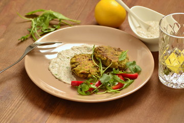 Lentil fritters with zucchini. Served with fresh vegetables and sauce.