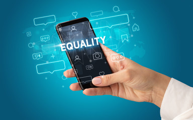 Fototapeta na wymiar Female hand typing on smartphone with EQUALITY inscription, social media concept