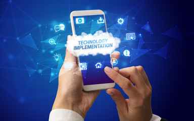 Naklejka premium Female hand holding smartphone with TECHNOLOGY IMPLEMENTATION inscription, cloud technology concept